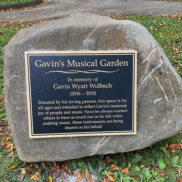 a large rock with a plaque dedicating a new music park to a you boy called Gavin Wolback