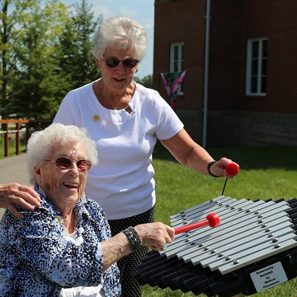 older lady in a wheelchair playing an outdoor musical instrument