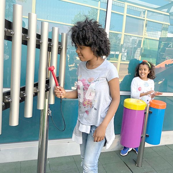 teenage girl playing on outdoor musical chimes at the santa maria discovery museum