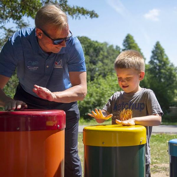 man and small boy playing colourful outdoor drums in the belleville rotary music garden