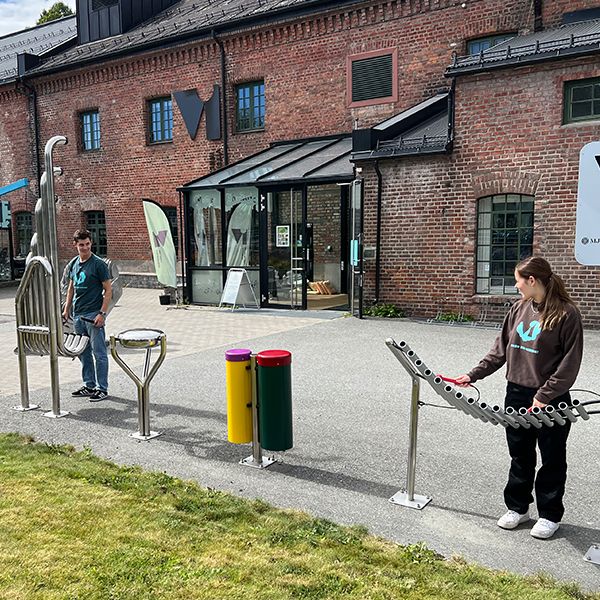 Male and female teenagers playing outdoor musical instruments outside the Vitensenteret Innlandet Science Centre in Norway