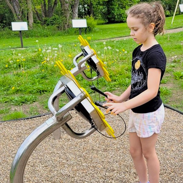 young girl playing large outdoor drums shaped like sunflowers on the hubbard library storywalk