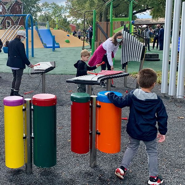 the back of a young child playing colorful conga drums in the music grove at lions pride park