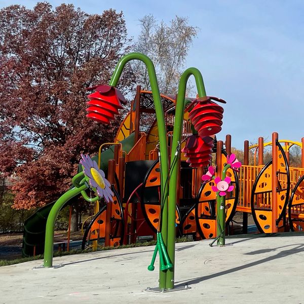 Close up picture of an outdoor musical instrument in a playground shaped like a flower with red petals