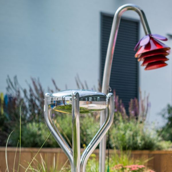 a stainless steel tongue drum and musical chimes shaped as a bell flower in a children's hospital garden