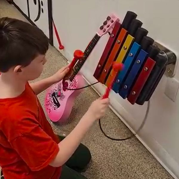 a boy playing a colourful small metallophone attached to a wall in the baraboo childrens museum