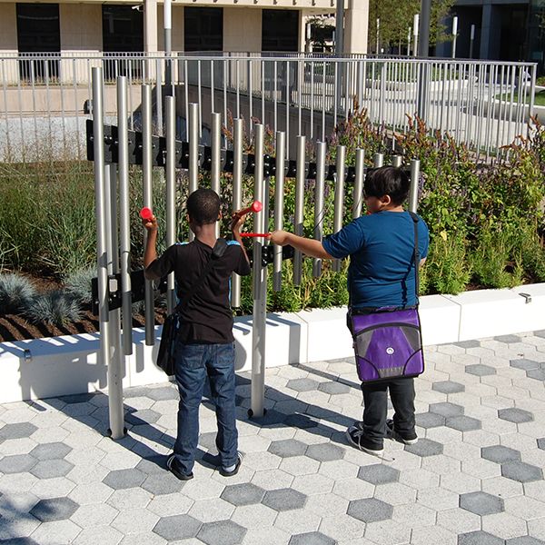 Two young men playing on the silver outdoor musical chimes on the plaza outside White Plains Public Library NY