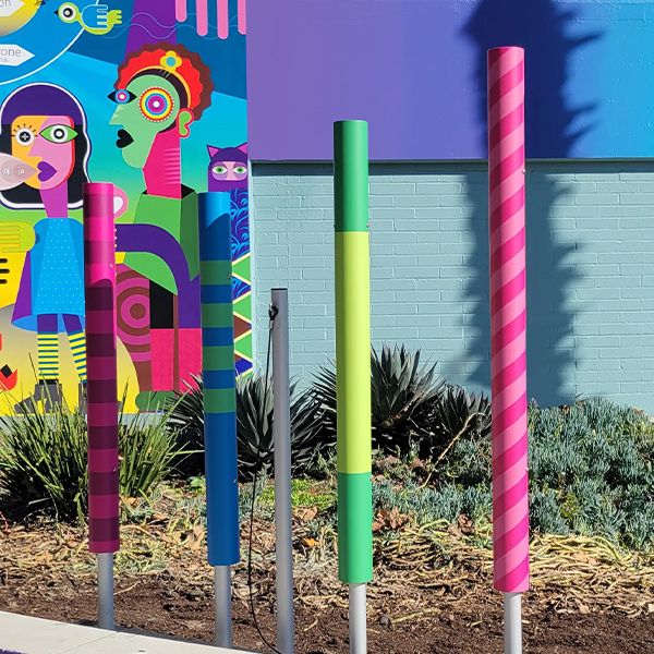 outdoor musical chimes installed in the ground and wrapped in varied colorful vinyl