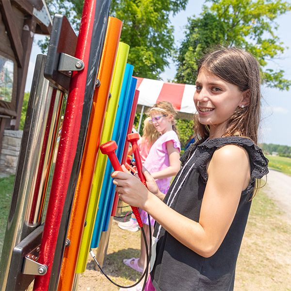 a girl playing rainbow colored outdoor musical chimes