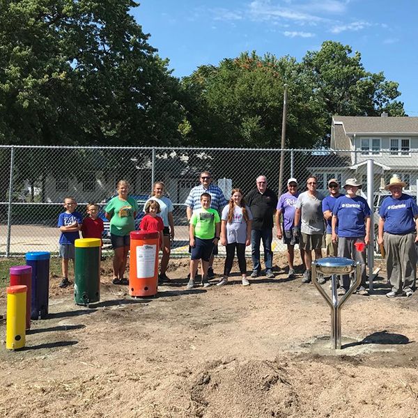 Hastings Noon Kiwanis team standing next to a recently completed outdoor musical playground in the Alcott Elementary School Playgound