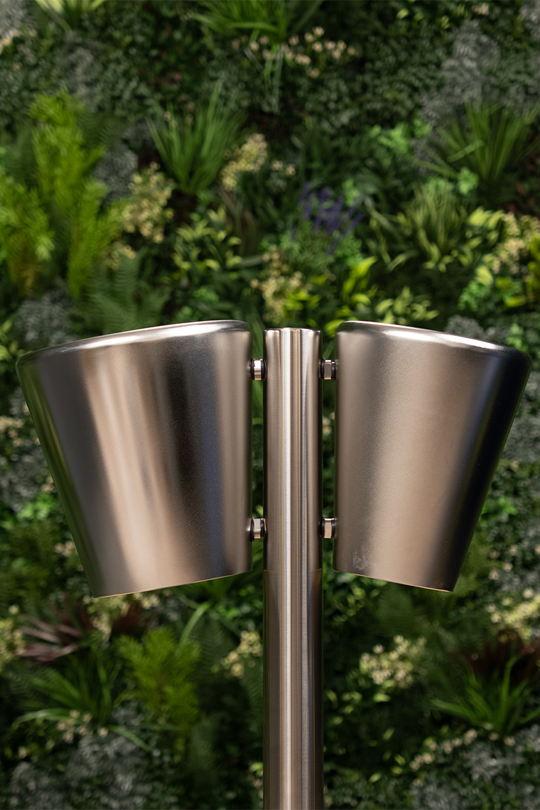 A pair of large metallic outdoor drums on a single post surrounded by a lush vertical garden.