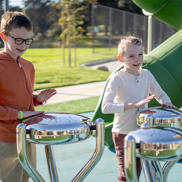 Two boys playing on stainless steel outdoor tongue drums in McLaren Park