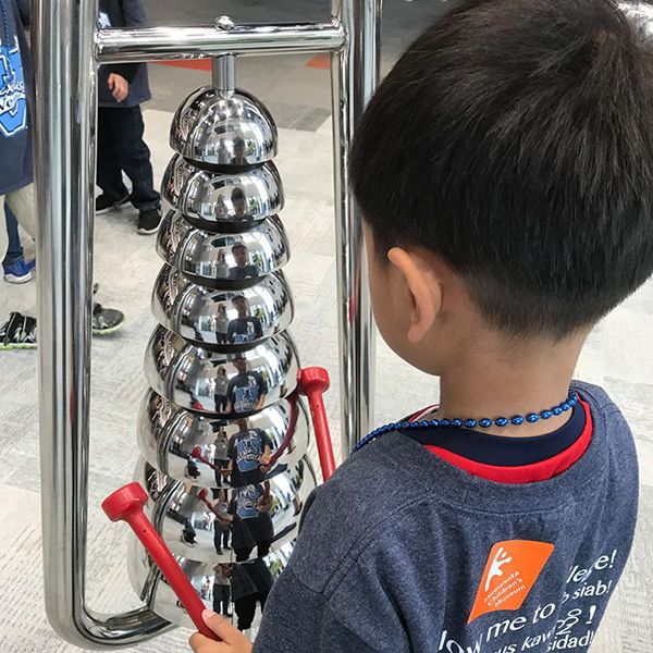 little boy playing on the silver bell lyre musical instrument in the minnesota children's museum