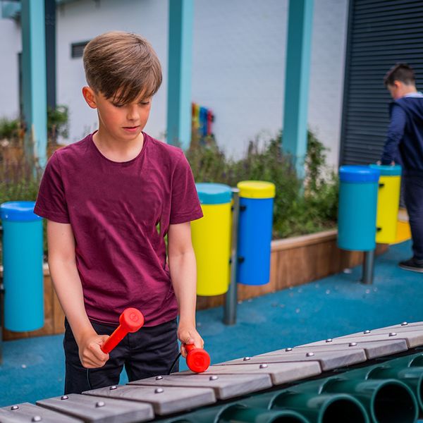 teenage boy plays large marimba outdoor xylophone in the jess mackie music garden edinburgh children's hospital