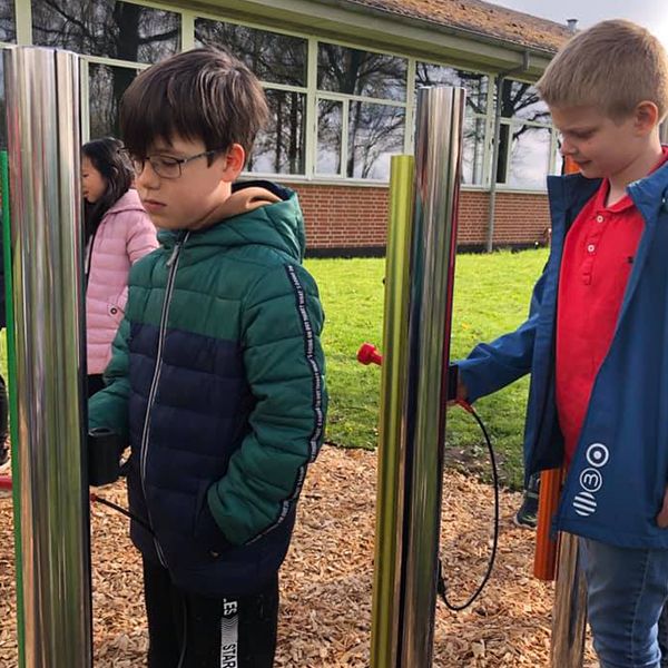 schoolboys playing bright colorful outdoor musical chimes in the school playground