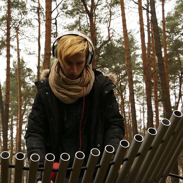 Young man playing large silver xylophone in a park