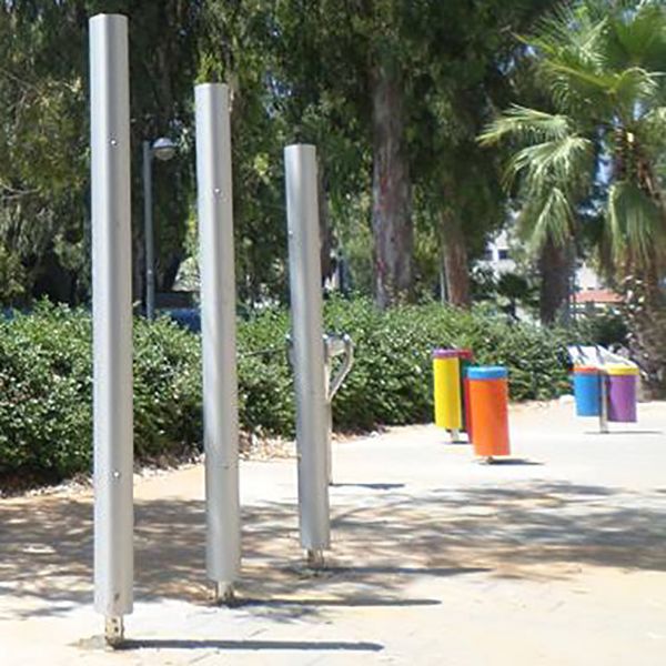 Three tall silver chimes installed on a pavement in tel aviv