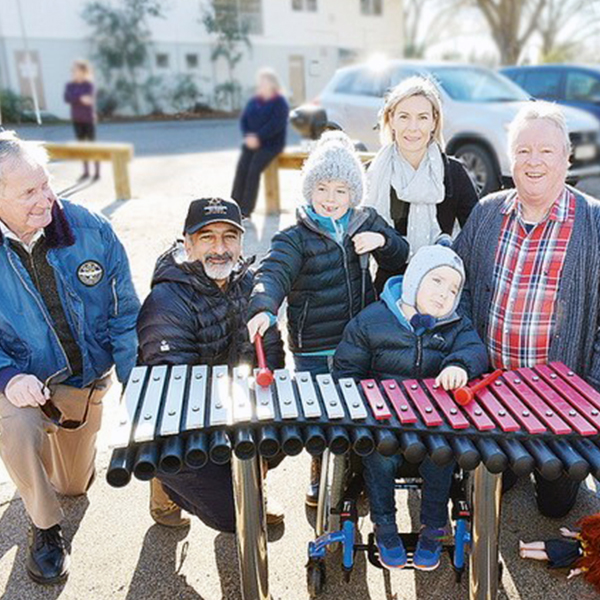 A group of fundraisers stood behind an outdoor xylophone in a new inclusive playground