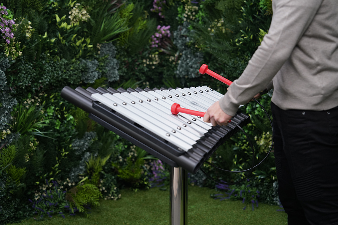 close up image of an outdoor xylophone being played with red mallets