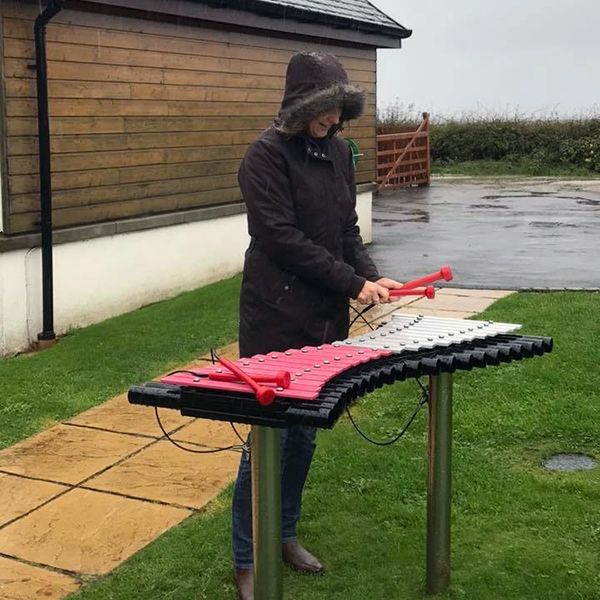 adult playing the duo outdoor xylophone in the rain at Calums Cabin 