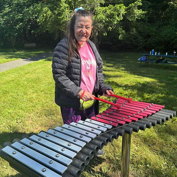 lady playing an outdoor xylophone in the camp beausite new musical garden