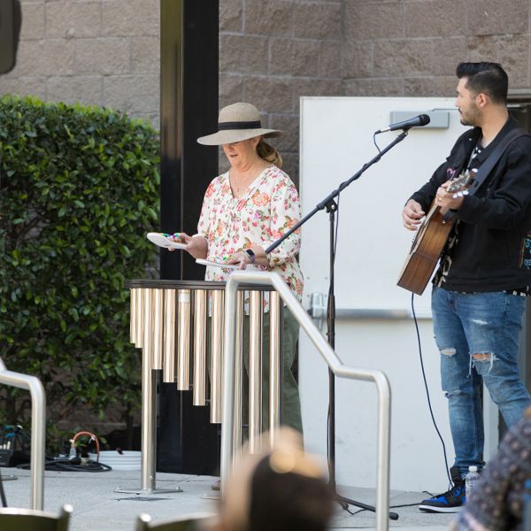 lady wearing a large hat playing an outdoor musical instrument handpipes by using her flip flops