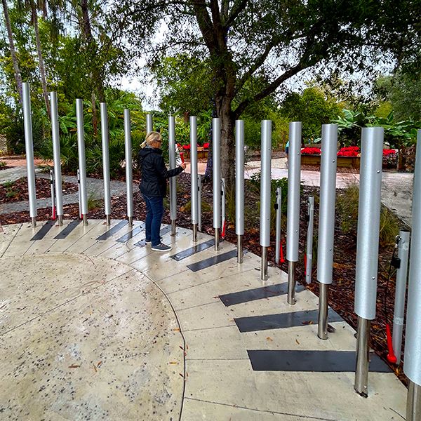 Lady Playing Huge Outdoor Musical Chimes in the Florida Botanical Garden Sensory Garden 