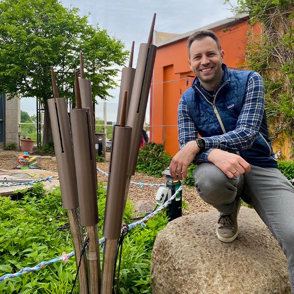 Director of the Madison Childrens Museum next to a set of musical chimes shaped like cattails