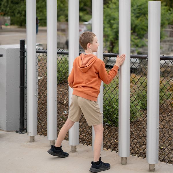 a young boy playing musical tubular bells in Mclaren park