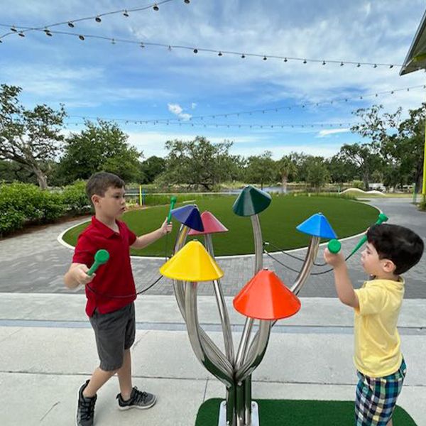 two young boys playing on an outdoor musical instrument shaped like colorful mushrooms at the Louisiana Children's Museum