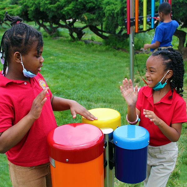 two elementary school children from the Lift for Life Academy playing outdoor musical drums