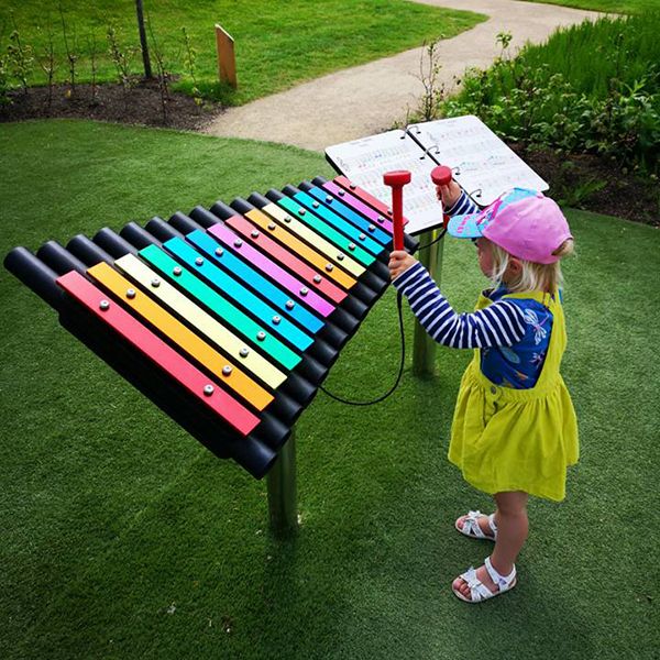 a young girld playing a rainbow coloured outdoor musical xylophone in the playful garden at Brodie Castle National Trust Scotland