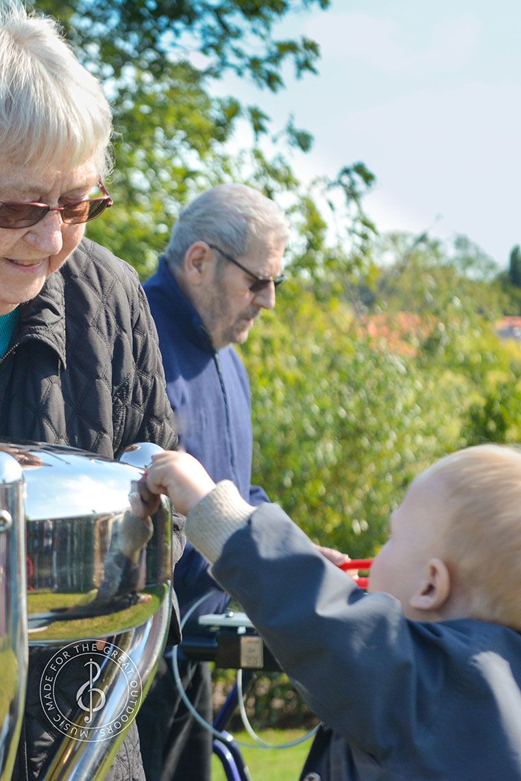 Older Lady and Small Child Playing Stainless Steel Tongue Drum Outdoors