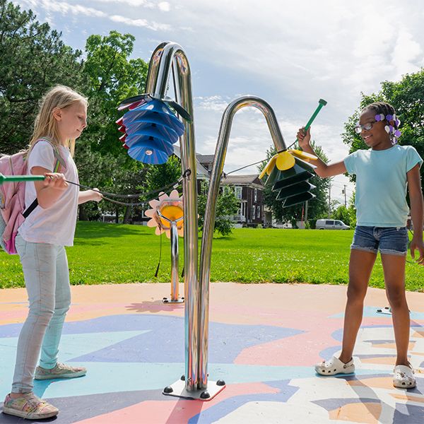 two teenage girls playing a set of outdoor musical flower chimes in a music park