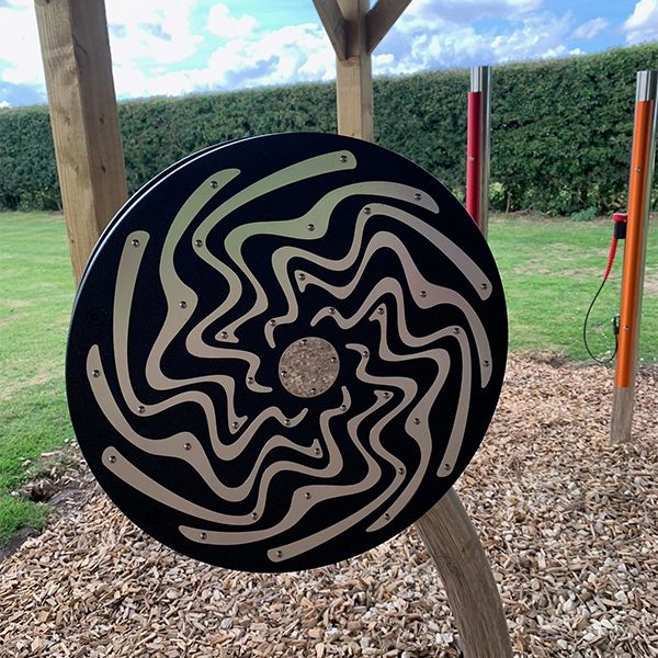 A large circular black and silver rain wheel displayed in the new music area at the Thomas Centre