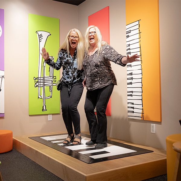 two ladies jumping on a floor piano in the NAMM museum