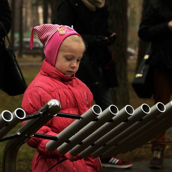 Little girl playing a large metallophone in a park