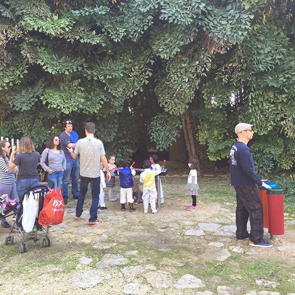 families gathered around large outdoor musical instruments including drums and chimes in play park