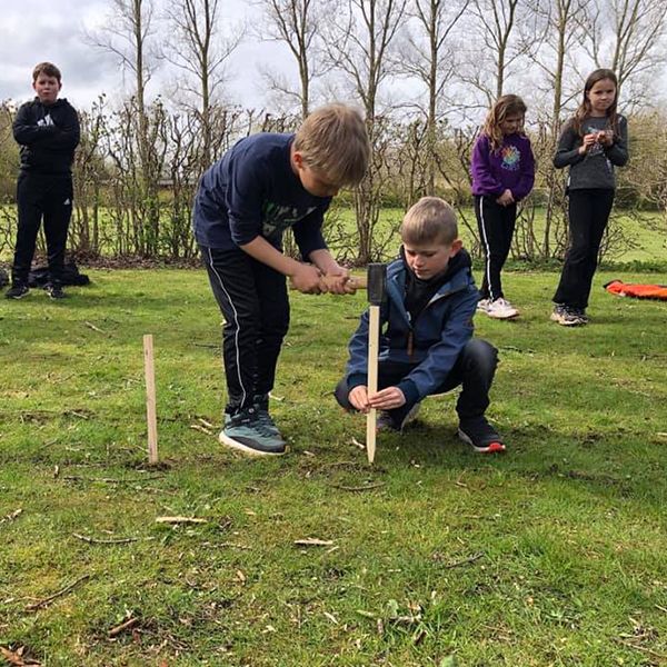 two schoolboys hammering stakes into the ground ready for new outdoor musical instruments