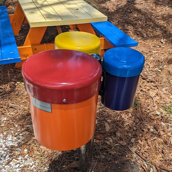 set of three outdoor drums in different colors on a stainless steel post