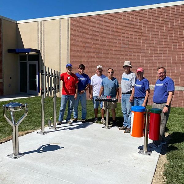 Hastings Noon Kiwanis team standing next to a recently completed outdoor musical playground in the Adams Central Elementary School Playgound