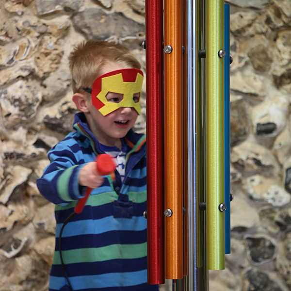 young boy dressed as a superhero playing an outdoor musical instrument on world book day 