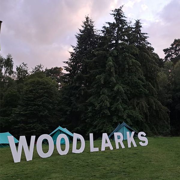 large white free standing letters spelling the work woodlarks in a camp site