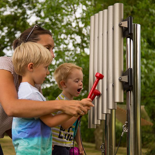 two little boys and their mum playing on an outdoor musical instrument