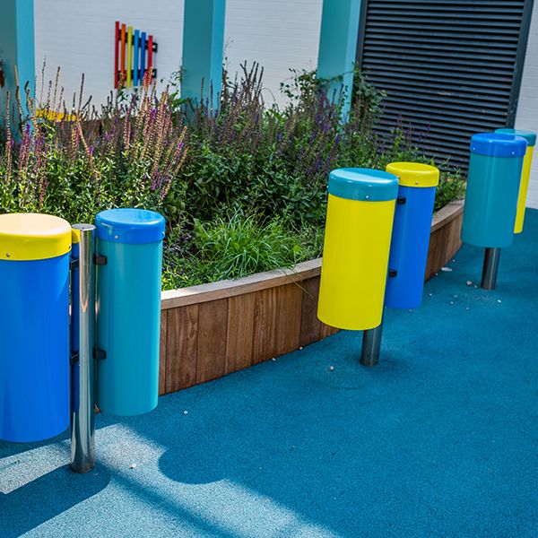 three sets of two conga drums in painted blue and yellow in a children's hospital garden