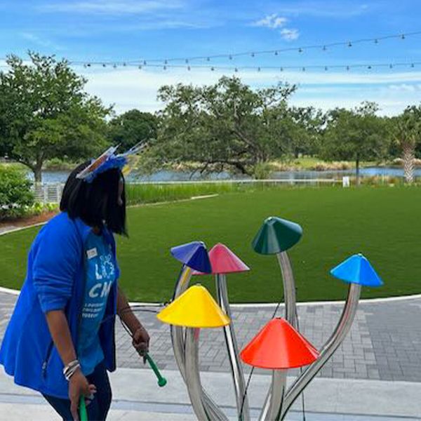 a member of staff playing on an outdoor musical instrument shaped like colorful mushrooms at the Louisiana Children's Museum