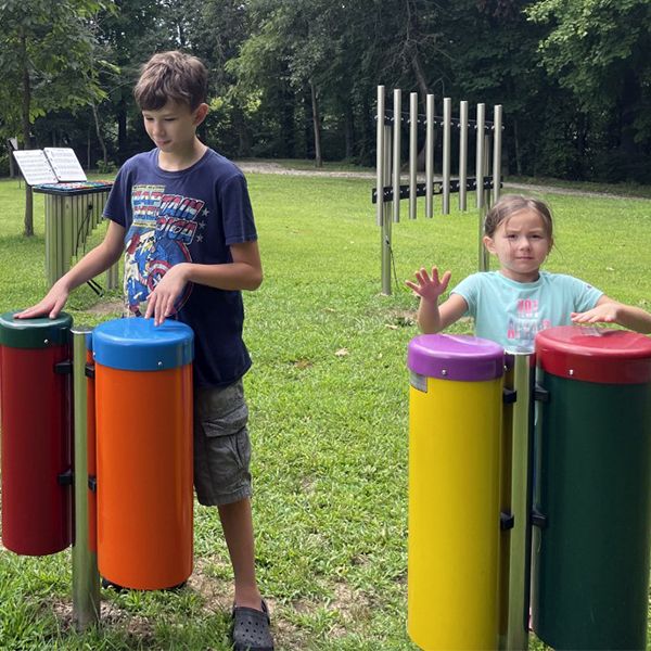 Two children playing colorful drums in a playground