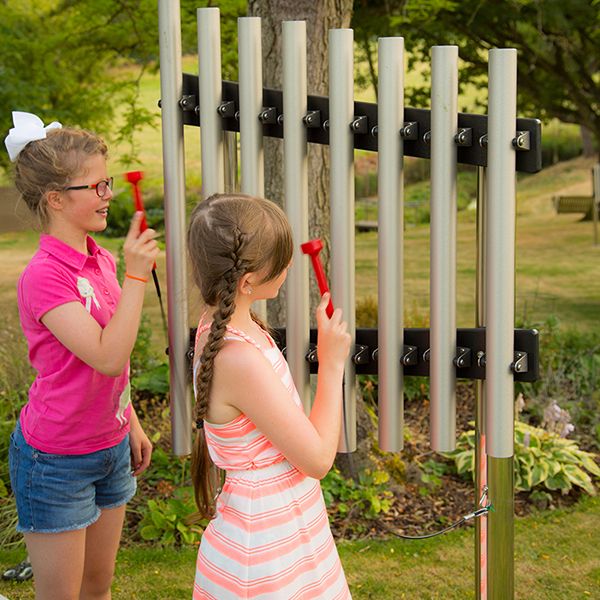 two girls playing on a musical chime set in a garden