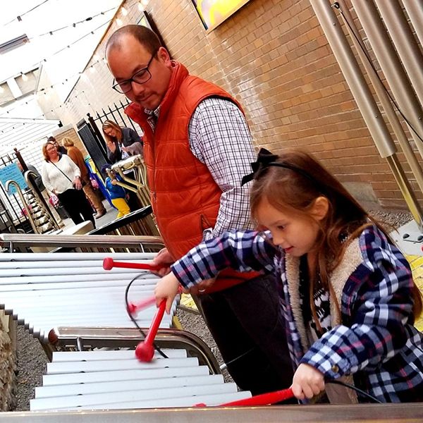 Father and Daughter playing on a large outdoor metallophone in the new Go Art! Play Me A Tune Music Garden