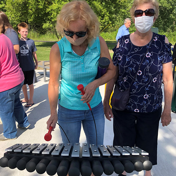 two ladies playing an outdoor xylophone in the Bridge to Bay Music Park Michigan